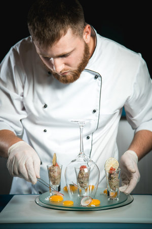 Cheerful bearded chef cook cooking while cooking meals in the kitchenの写真素材