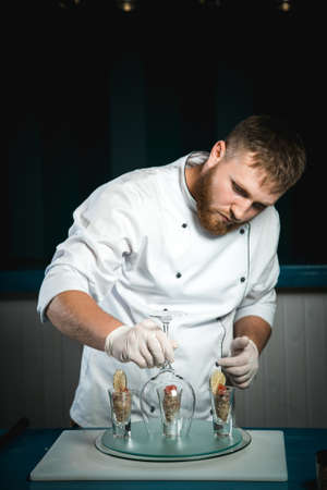 Cheerful bearded chef cook cooking while cooking meals in the kitchenの写真素材