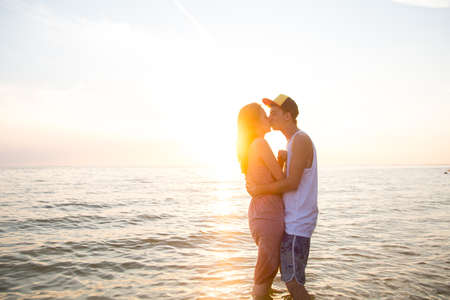 Young loving couple kissing at sunset in the sea. The concept of love and affection, a dateの写真素材