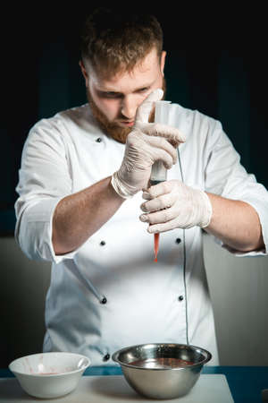 Cheerful bearded chef cook cooking while cooking meals in the kitchenの写真素材