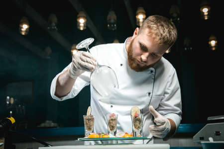 Cheerful bearded chef cook cooking while cooking meals in the kitchenの写真素材