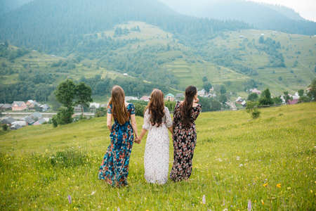 Girls girlfriends in dresses walk on a beautiful mountain meadowの写真素材