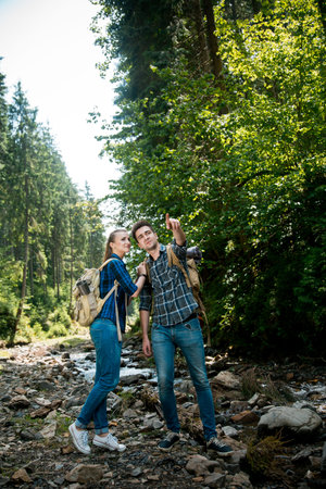 Man and woman tourists walking hand in hand through the woods in the mountains