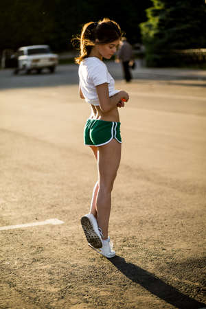 Beautiful young brunette girl doing sport outdoors in summerの写真素材