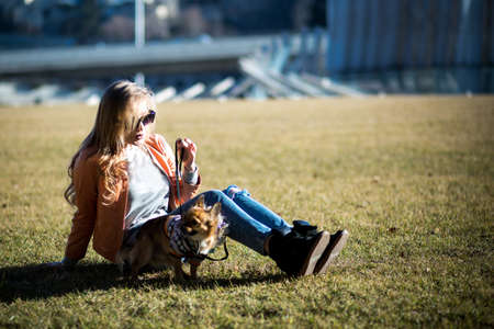 Beautiful young blond woman walks her dog in the Parkの写真素材