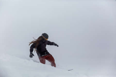 snowboarder snowboarding on fresh snow on ski slope on Sunny winter day in the ski resort in Georgiaの写真素材