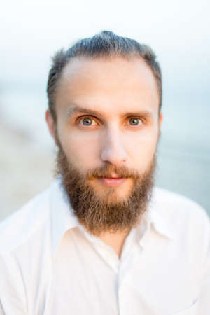 Portrait of pensive man with a beard on the beach by the seaの写真素材