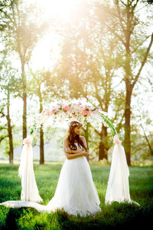 Beautiful bride in wedding dress and with a lovely mood in natureの写真素材