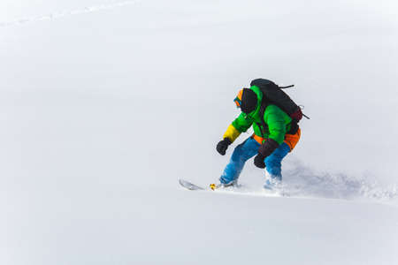 snowboarder snowboarding on fresh snow on ski slope on Sunny winter day in the ski resort in Georgiaの写真素材