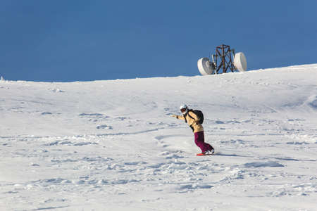 women snowboarder snowboarding on fresh white snow with ski slope on Sunny winter dayの写真素材