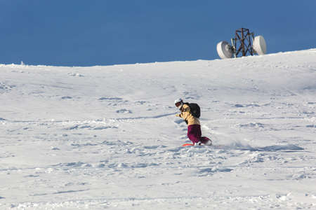 women snowboarder snowboarding on fresh white snow with ski slope on Sunny winter dayの写真素材