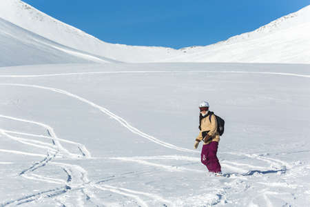 women snowboarder snowboarding on fresh white snow with ski slope on Sunny winter dayの写真素材