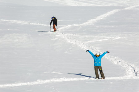 A skier and  snowboarder during descent at a ski resort. Beautiful winter landscape with snow-topped...