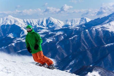 Male snowboarder snowboarding on fresh snow on ski slope on Sunny winter day in the ski resort in Georgia. Travel adventure concept. space for textの写真素材