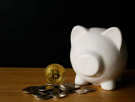 pot full of gold coins on a wooden surface and dark backgroundの写真素材