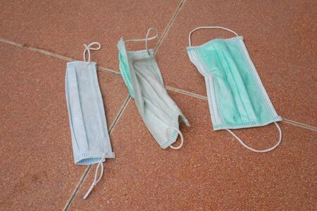 used surgical mask on the floor. discarded face mask.の写真素材