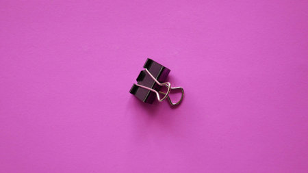 Black Binder clip on pink background