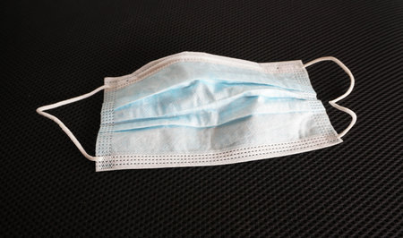 used surgical mask on black background.