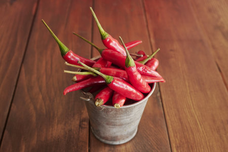 red hot chili peppers in a bucket on a brown wooden background.の写真素材