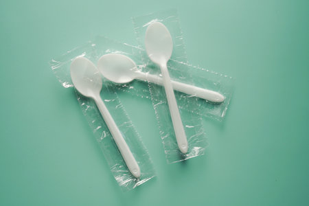 plastic spoon and fork in plastic bag on green background, food plastic conceptの写真素材