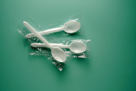 plastic spoon and plastic bag on green background, closeup of photoの写真素材