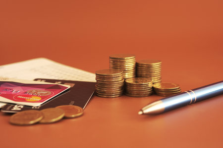 Credit card, coins and pen on a brown background with copy spaceの写真素材