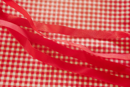 Red satin ribbon on checkered tablecloth background close upの写真素材