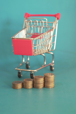 Shopping cart with coins on a green background. Business concept.の写真素材