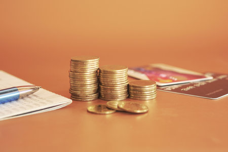 money coin stack with credit card and note book on wood table backgroundの写真素材