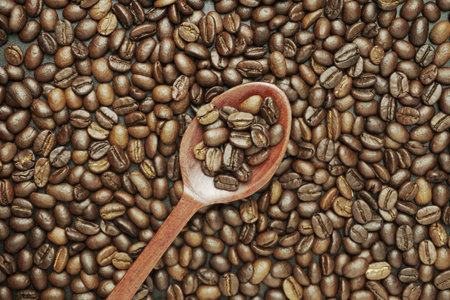 Roasted coffee beans and wooden spoon on dark background, top viewの写真素材