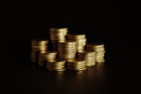 Stacks of golden coins on black background, business and finance concept idea.