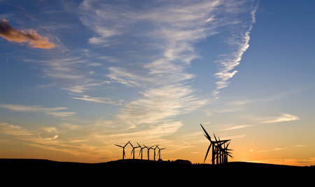 Silhouette of wind turbines against a sunsetの写真素材