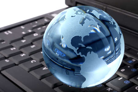 Blue glass globe on a laptop keyboardの写真素材