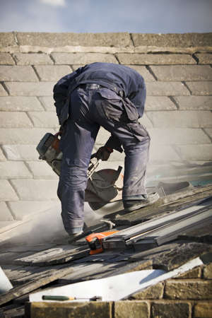 Roofer cutting roof tiles with circular sawの写真素材