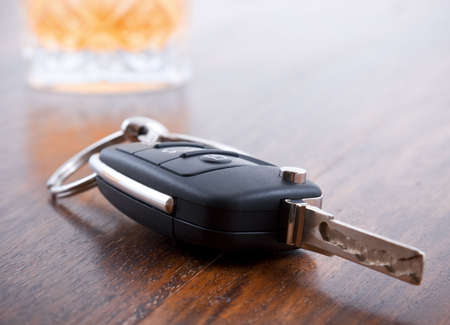 Drunk driving concept - car keys in the foreground with glass of whiskeyの写真素材