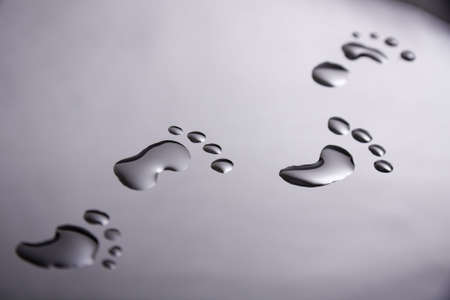 Footsteps in water droplets on a shiny surfaceの写真素材