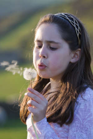 Young girl holding dandelion making a wishの写真素材