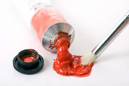 Paintbrush being dipped into red paint from tubeの写真素材
