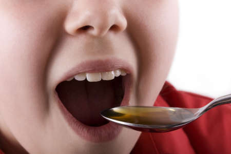 Young girl about to take medication or cod liver oil from a spoonの写真素材