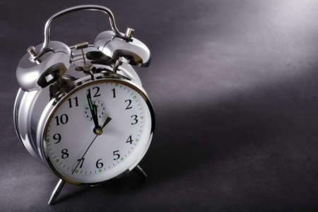 Alarm clock at night just before midnight on a dark backgroundの写真素材