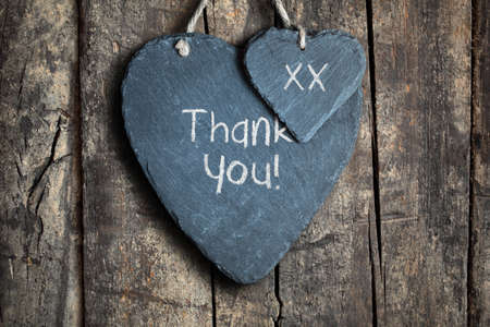 Thank you note written in chalk on a slate heart hanging on a wooden backgroundの写真素材