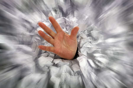 Businessman drowning in paperwork reaching for assistance and supportの写真素材