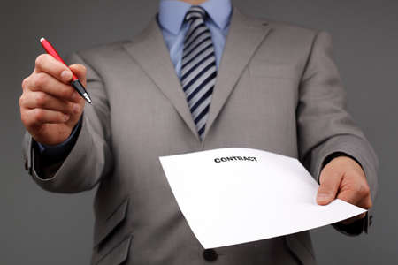 Businessmans hand holding a pen requesting a signature on a contract or documentの写真素材