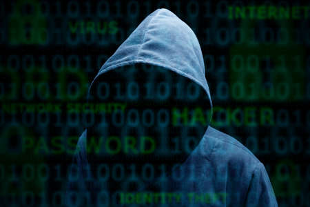 Computer hacker silhouette of hooded man with binary data and network security termsの写真素材