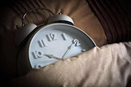 Alarm clock in bed concept for bed time, asleep, sleeping or insomniaの写真素材