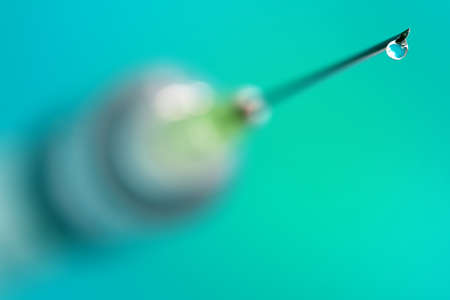 Medical injection syringe with drop falling from the needle shallow depth of fieldの写真素材
