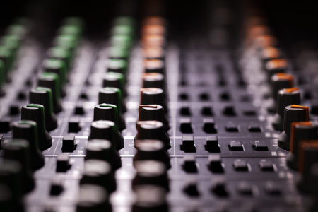 Recording studio audio mixing console looking across the control knobs