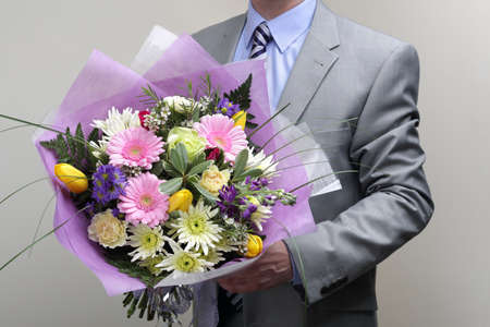 Businessman wearing a suit holding a bouquet of flowersの写真素材