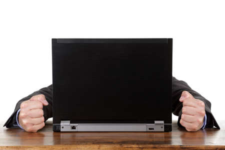 Frustrated businessman hiding behind laptop with clenched fistの写真素材
