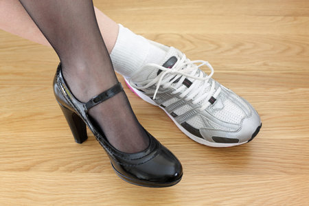 Woman wearing one business shoe and sports shoe concept for work-life balance, healthy lifestyle and...